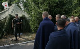 ”Refugees” stand near the tent of first-aid post