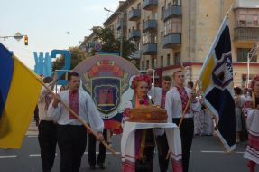 A girl in the Ukrainian national suit carries round loaf