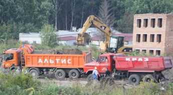 A power-shovel throws down earth in a truck