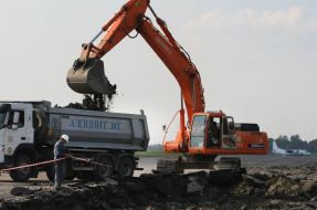 A power-shovel throws down earth in a truck