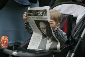 A boy examines a newspaper