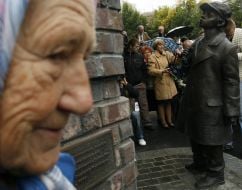 An elderly woman passes near a monument