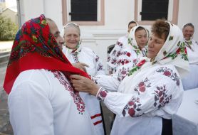 A woman puts a shawl on to the man