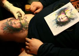 Participant of the festival makes a tattoo