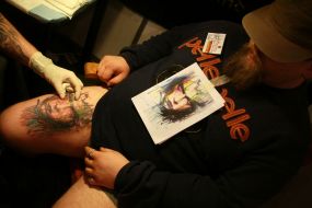 Participant of the festival makes a tattoo