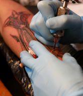 Participant of the festival makes a tattoo