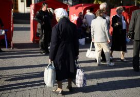 An elderly woman goes near tents
