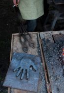 Кузнец курит, стоя возле металлической пластины