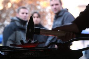 Кузнец бьет молотком по металлической пластине