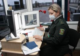 A border guard in a respirator mask checks up passports