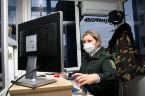 A border guard in a respirator mask checks up passports