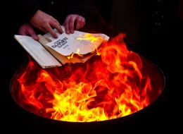 Участник акции сжигает книгу