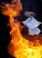 Участник акции сжигает книгу