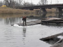 A worker draws fuel oil from Kalmius river