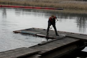 A worker draws fuel oil from Kalmius river