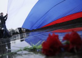 Гвоздики под растянутым флагом Российской Федерации