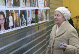 Пожилая женщина рассматривает фотографии жертв взрыва