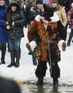 A man in the suit of Wolf carries a girl across the river