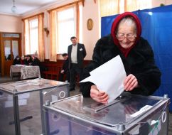 An elderly woman gives up a bulletin in ballot box