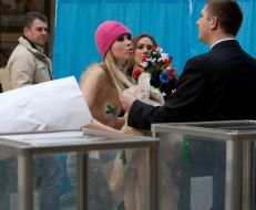 A guard forces an activist ”FEMEN” womanish motion to put on clothes