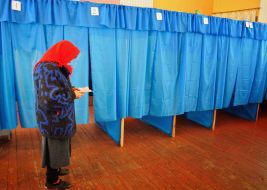 An old woman examines a ballot paper