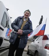 An elderly man holds a flag of Russia