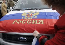 Woman clings flag of Russia to hood of car