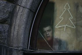 A young man peeks out from the window of bookstore