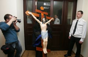 A priest carries a cross with the crucifix