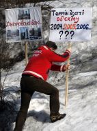 Участник митинга устанавливает плакат