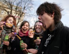 Молодой человек надувает мыльные пузыри