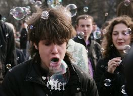 Молодой человек надувает мыльные пузыри