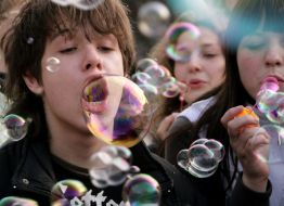 Молодой человек надувает мыльные пузыри