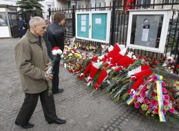 A man lays flowers near the picture of President of Poland