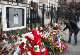A man lays flowers near the picture of President of Poland
