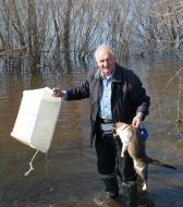 Чоловік переносить кота через річку