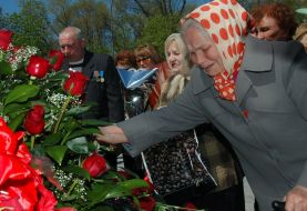 Пожилая женщина возлагает цветы