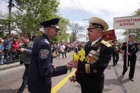 Співробітник міліції вручає квіти ветеранові ВВВ