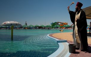 A priest sanctifies water in a pool