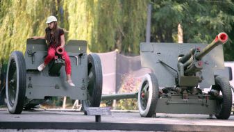 A girl sits on the trunk of the regimental cannon