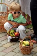 The girl sitting next to baskets of fruit