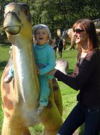 A girl sits on the sculpture of dinosaur