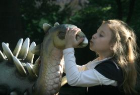 A girl kisses the sculpture of dinosaur
