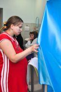 A pregnant woman enters the voting booth