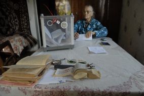 Літня жінка заповнює бюлетень для голосування