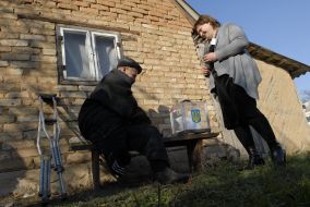 Літній чоловік заповнює бюлетень для голосування