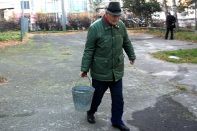 Мужчина несёт ведро с водой