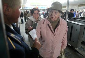 Літня жінка показує пенсійне посвідчення, 