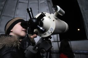 The young man looks through a telescope on the Moon