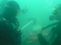 Journalists divers show a newspaper made-up under the water